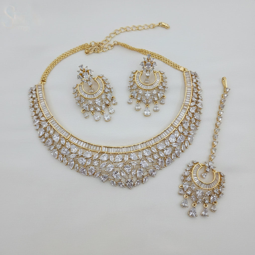 Gold necklace set with mang tikka on a beige background, branded as 'Sparkle'.