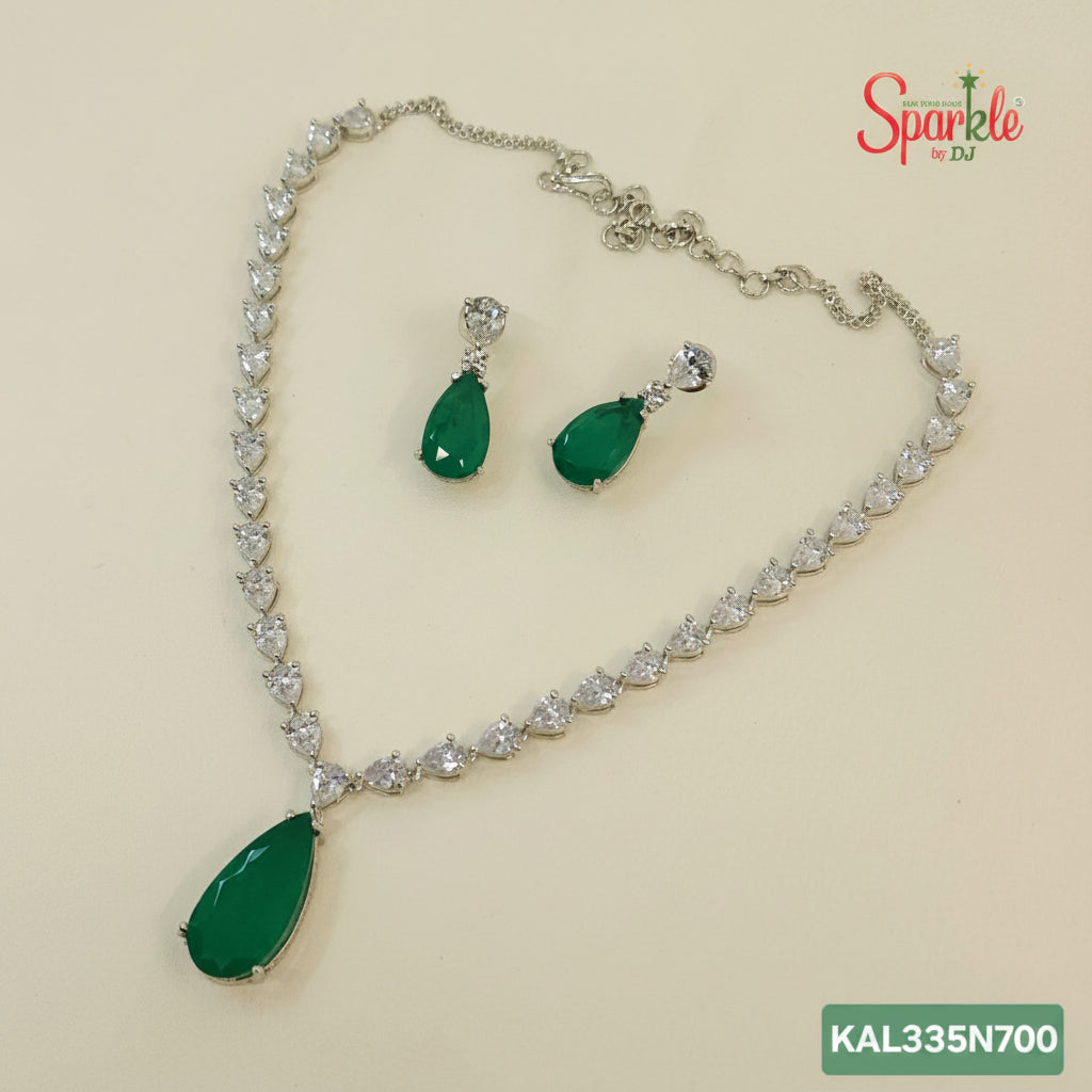 Jewelry set with necklace and earrings featuring green teardrop pendants on a beige background.