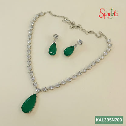 Jewelry set with necklace and earrings featuring green teardrop pendants on a beige background.
