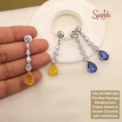 Two pairs of pear-shaped earrings with yellow and blue stones held by a hand, branded 'SparklebyDJ'.