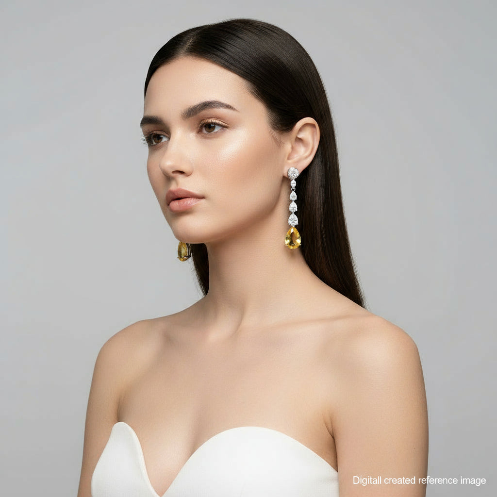 Pair of drop earrings with yellow gemstones and clear stones on a light gray background