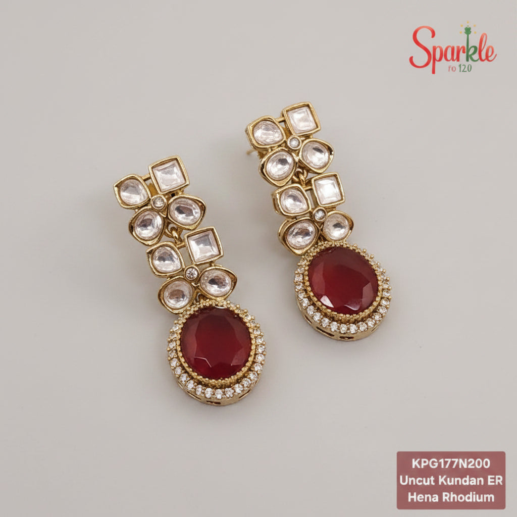 Pair of gold earrings with red gemstones on a beige background