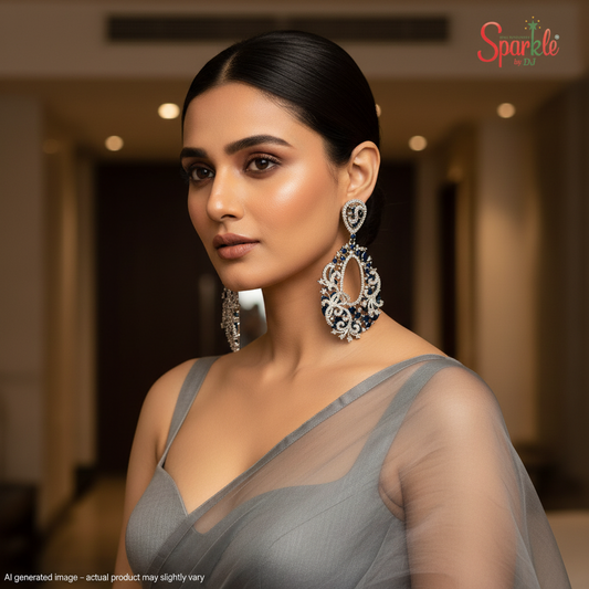 Woman wearing a gray saree with large earrings in an indoor setting, with 'SparklebyDJ' brand logo.