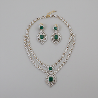 Jewelry set with necklace and earrings featuring green gemstones on a gray background