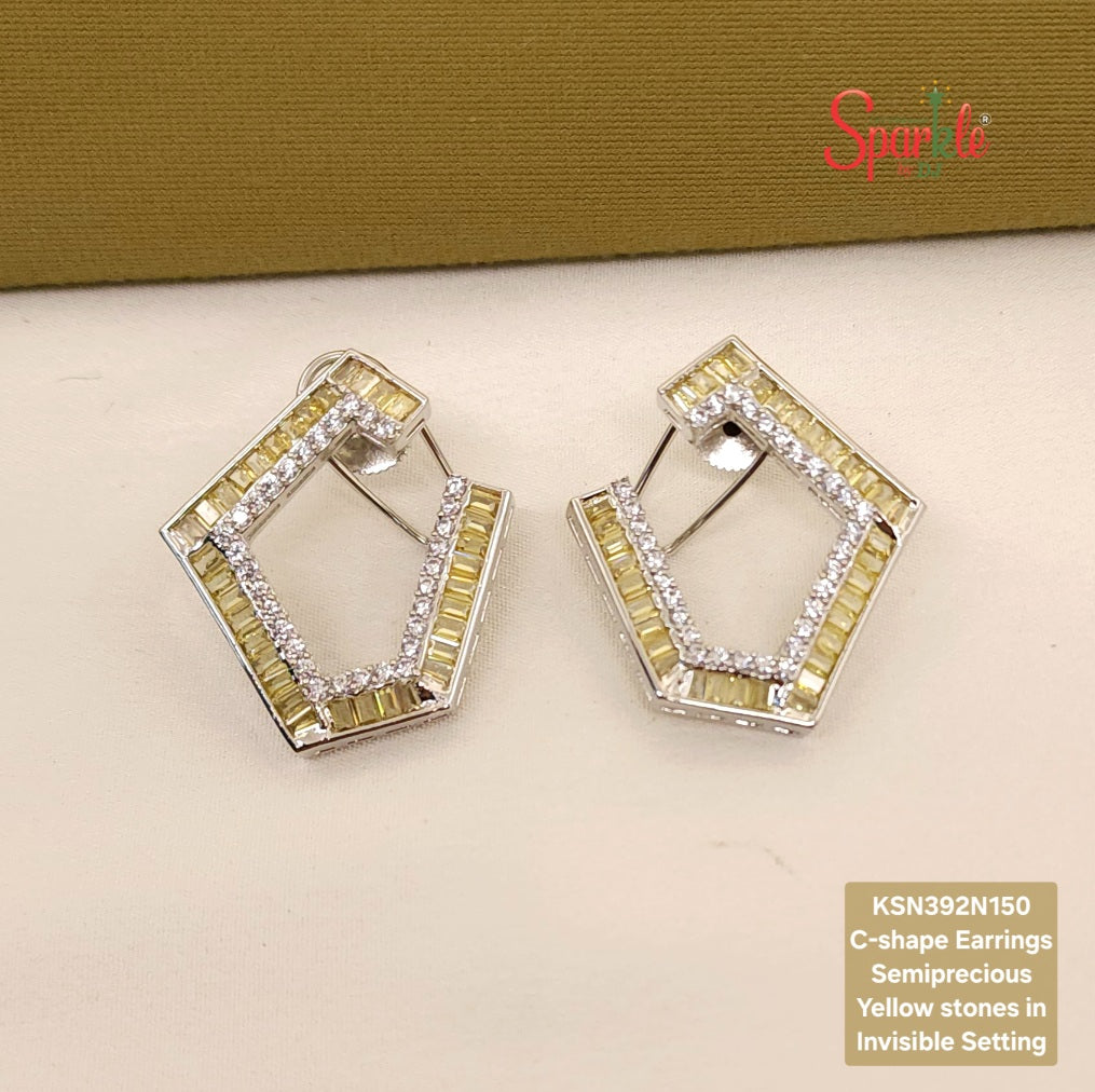 C-shape earrings with yellow stones on a beige surface, branded 'SparklebyDJ'.