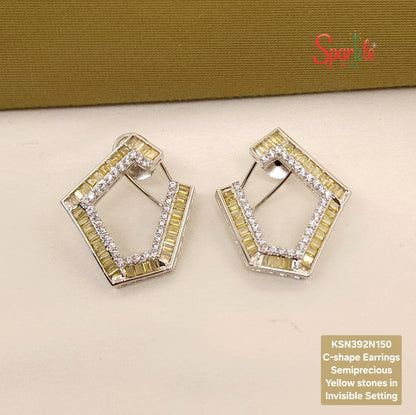 C-shape earrings with yellow stones on a beige surface, branded 'SparklebyDJ'.