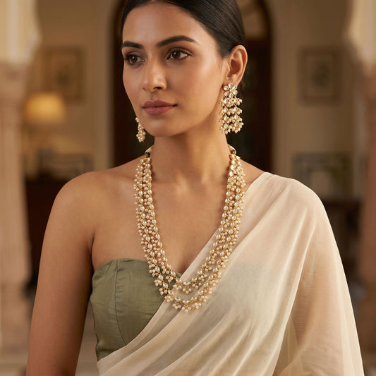 Model in a saree displaying a multi-layered Kundan and pearl necklace, emphasizing traditional craftsmanship and sophisticated style.