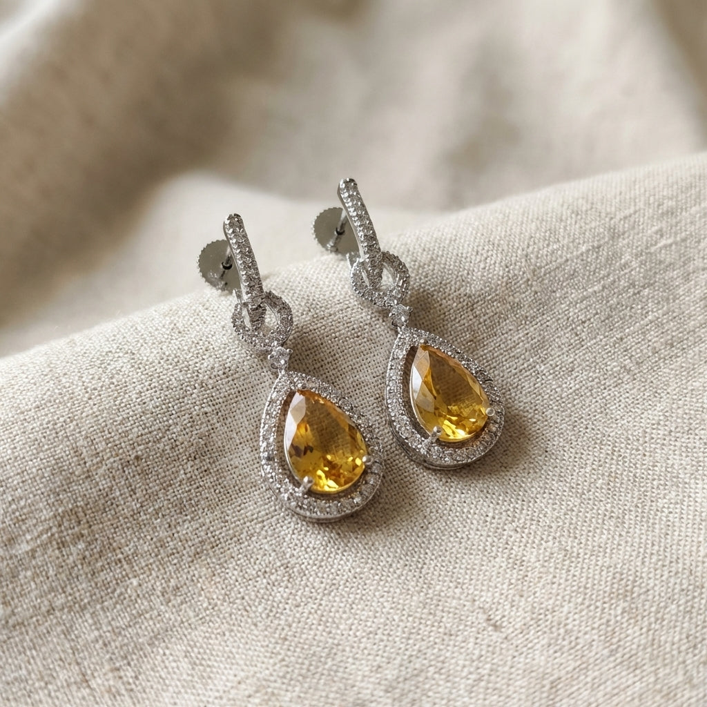 Detailed macro shot of a tiny pearl-drop CZ earring with micro facets, white rhodium finish, on textured linen fabric, elegant and delicate.